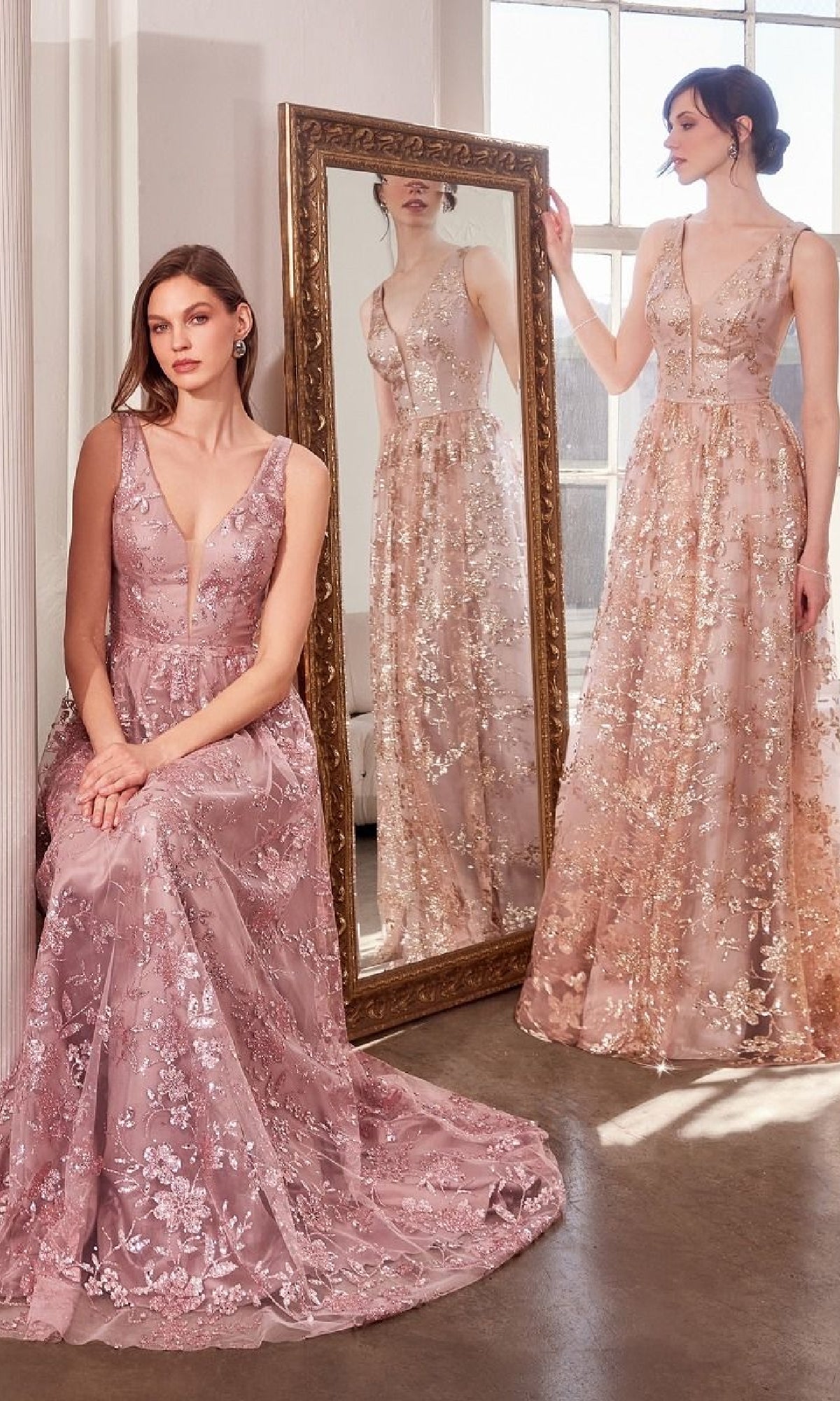 Two women showcase the Amoris T606 Embroidered-Lace Long Prom Dress in pale pink. One stands by a large mirror, while the other is seated, both elegantly displaying the sleeveless evening gown’s graceful design.